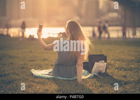 USA, New York City, blonde girl taking a selfie on Brooklyn area in summer Stock Photo
