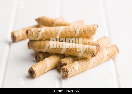 Sweet chocolate waffle rolls on white table. Stock Photo