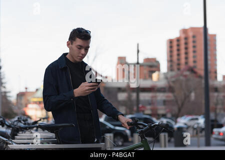 Man standing next to his bike and using mobile phone Stock Photo