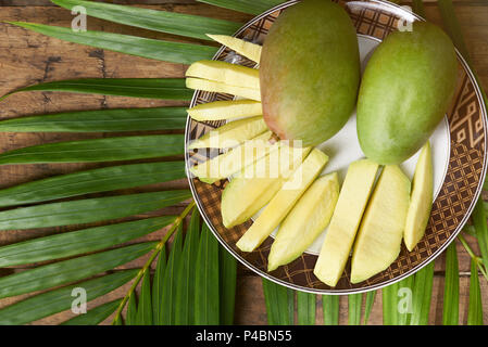 Sliced mango on plate stay on wooden background above top view Stock Photo