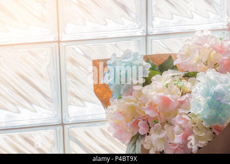 Flowers plastic bouquet on brick glass wall background. Stock Photo