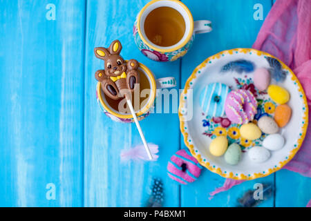 Easter sweets for the holiday. Spring. Bright colors on coffee mugs. Chocolate bunny. View from above. Stock Photo