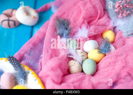 Chocolate eggs of different colors. Pink background and feathers. Easter. Spring decor. Stock Photo
