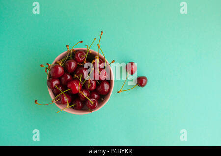 A bowl with cherries on turquoise background with space for your text. Stock Photo