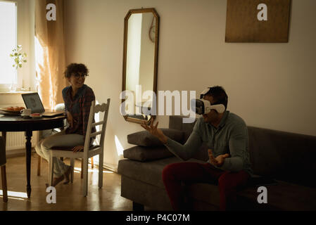 Woman looking at man while using virtual reality headset Stock Photo