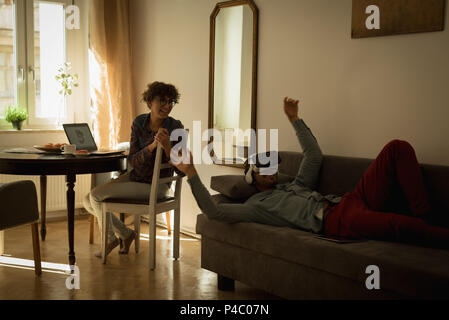 Woman looking at man while using virtual reality headset Stock Photo