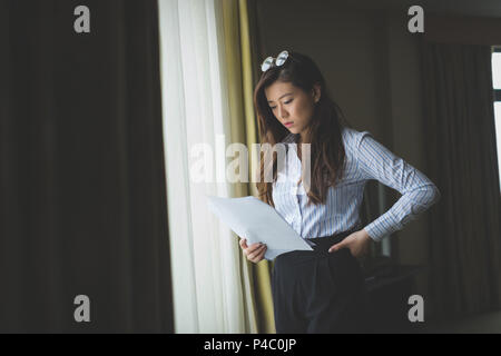 Businesswoman reading document near window Stock Photo