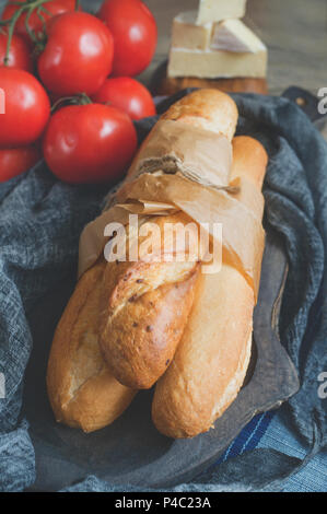 Baguette sandwich with lettuce and slices of fresh tomato. Preparation. Selective focus. A vertical frame. Stock Photo