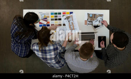 Two architects discussing layout while female coworkers looking at color palette Stock Photo