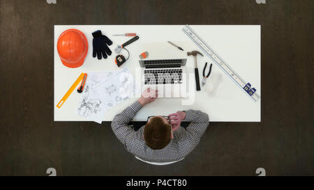 Architect in office working on laptop and answering phone call Stock Photo
