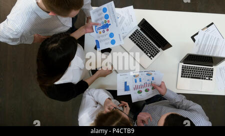 Four young office coworkers going through presentation materials Stock Photo