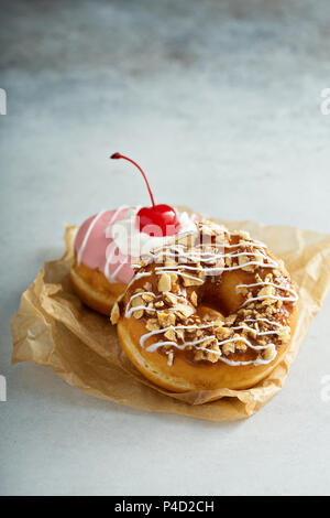 Assorted glazed fried donuts on parchment Stock Photo