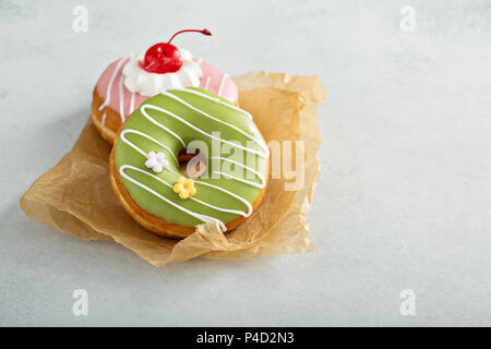 Assorted glazed fried donuts on parchment Stock Photo