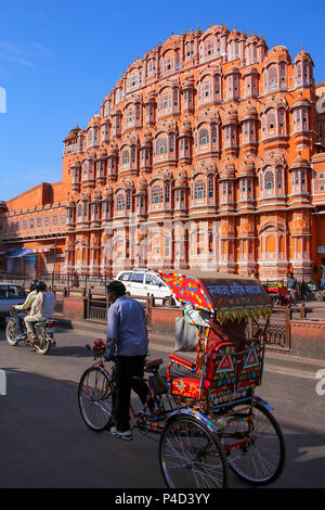 Cycle ricksaw in front of Hawa Mahal in Jaipur, Rajasthan, India. Hawa Mahal was designed by Lal Chand Ustad in the form of the crown of Krishna, the  Stock Photo