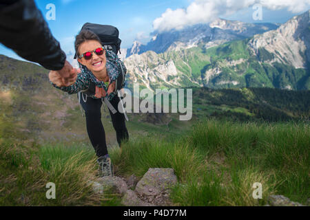 A helping hand helps a girl in the mountains taking her by the hand and dragging her. Stock Photo