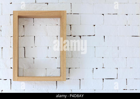 Brown wood frame on white brick background. Vintage furniture wooden frame hanging on white brick wall texture. Stock Photo