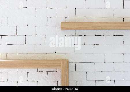 Brown wood frame on white brick background. Vintage furniture wooden frame hanging on white brick wall texture. Stock Photo