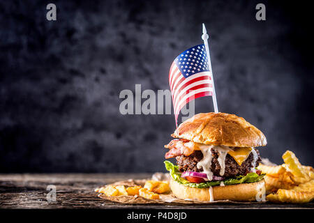 Close-up home made beef burger with american flag and fries on wooden table. Stock Photo