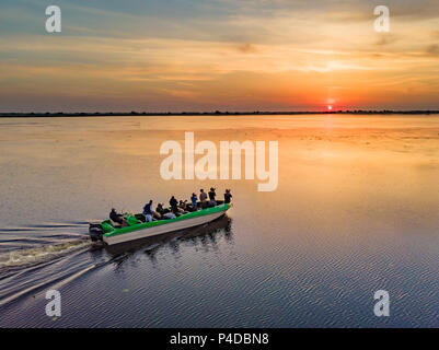 Tourists visiting Danube Delta in a motor boat, taking pictures at sunset in the Danube Delta, Romania Stock Photo