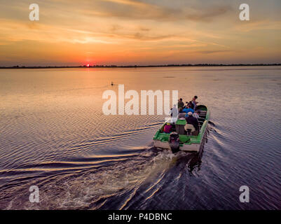 Tourists visiting Danube Delta in a motor boat, taking pictures at sunset in the Danube Delta, Romania Stock Photo