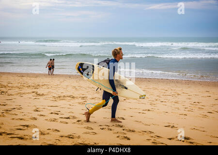 BORDEAUX, FRANCE - JUNE 13, 2017: Unidentified surfer walks on beach of the Atlantic coast of France near Lacanau-Ocean, Bordeaux, France Stock Photo