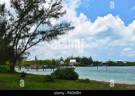 Turtle Bay in Green Turtle Cay in Bahamas.  Pier on Caribbean clear blue waters with boats docked, trees, and clouds in sky. Stock Photo