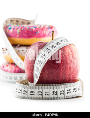 Red apple and three colorful donuts wrapped in a tailors measuring tape isolated on white. Stock Photo