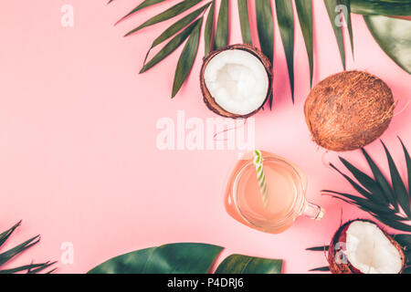 Coconut water and coconuts on a background with tropical leaves. Stock Photo