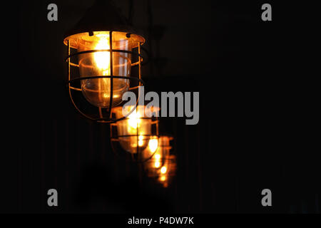 A row of retro style ceiling lights. Pendant shaped lanterns with cage and warm glowing light. Space for your text. Stock Photo