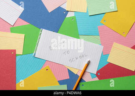 Notebook sheet with the message back to school against a background of colorful paper notes Stock Photo