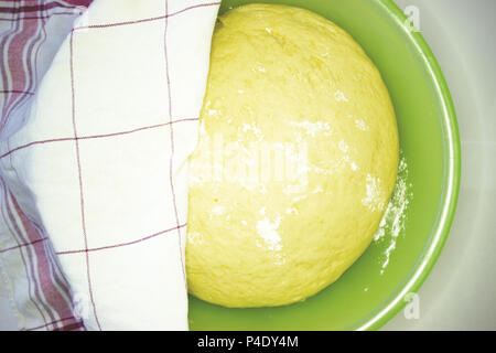 Dice the dough in the bowl. Working in a restaurant. The dough is covered with a cloth. Stock Photo