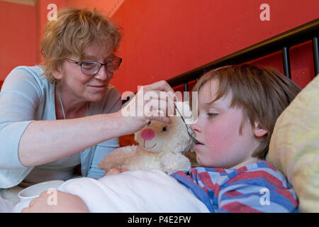 mother looking after her ill son in his bed Stock Photo