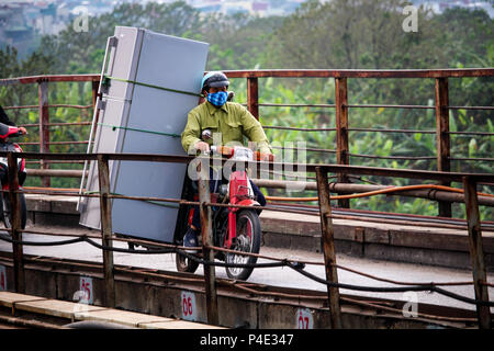 Hanoi, Vietnam - March 15, 2018: Vietnamese man transporting an enormous fridge on his motorbike Stock Photo
