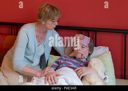 mother comforting her ill son in his bed Stock Photo