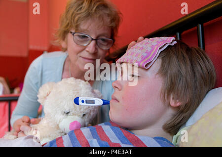 mother comforting her ill son in his bed Stock Photo