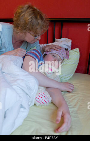 mother comforting her ill son in his bed Stock Photo