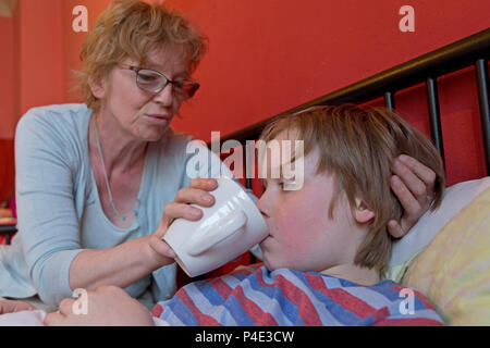 mother looking after her ill son in his bed Stock Photo