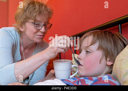 mother looking after her ill son in his bed Stock Photo