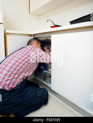 Plumber fixing a sink in kitchen with wrench Stock Photo