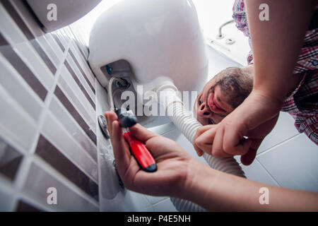 Plumber fixing a sink in bathroom with wrench Stock Photo