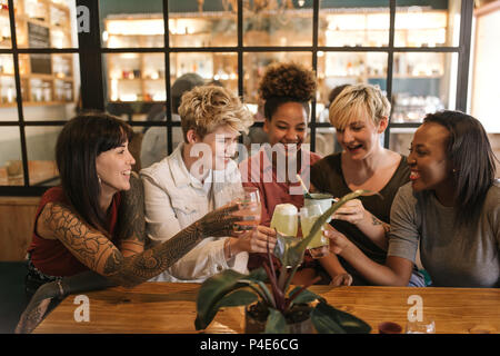 Diverse girlfriends toasting together at a trendy bistro table Stock Photo