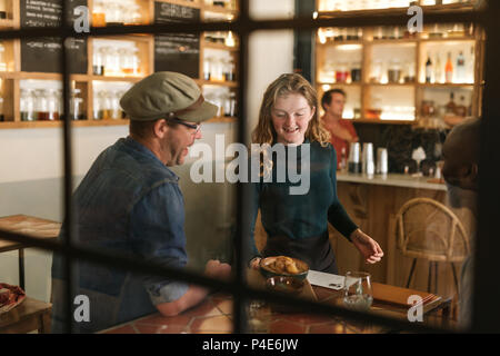 Smiling waitress serving food to a bistro customer Stock Photo