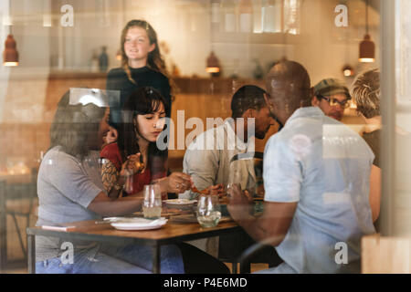Diverse young friends eating together at a bistro table Stock Photo
