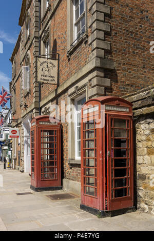 Two old red telephone boxes on the Market Square in the historic market town of Towcester, Northamptonshire, UK Stock Photo