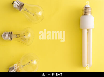Energy-saving Lamp vs. incandescent lamps. The concept of energy saving . On a yellow background.One energy-saving bulb corresponds to three incandesc Stock Photo