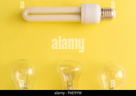 Energy-saving Lamp vs. incandescent lamps. The concept of energy saving . On a yellow background.One energy-saving bulb corresponds to three incandesc Stock Photo