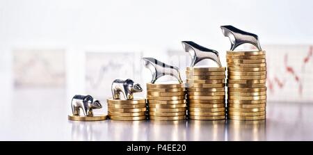 Stack of coins with Bull and Bear and graphics with market prices in the background | usage worldwide Stock Photo