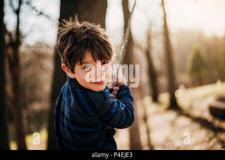 Boy playing on a rope swing in the forest Stock Photo