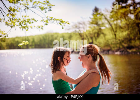 Mother standing by a lake carrying her daughter Stock Photo