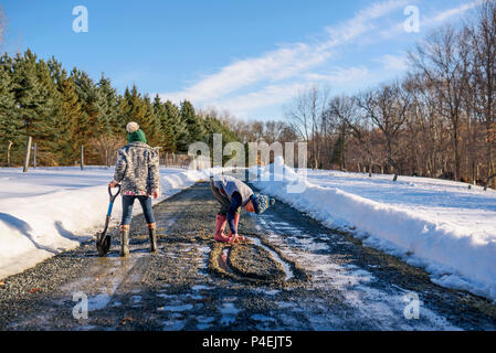 Boy and girl playing in the road in the melting snow Stock Photo